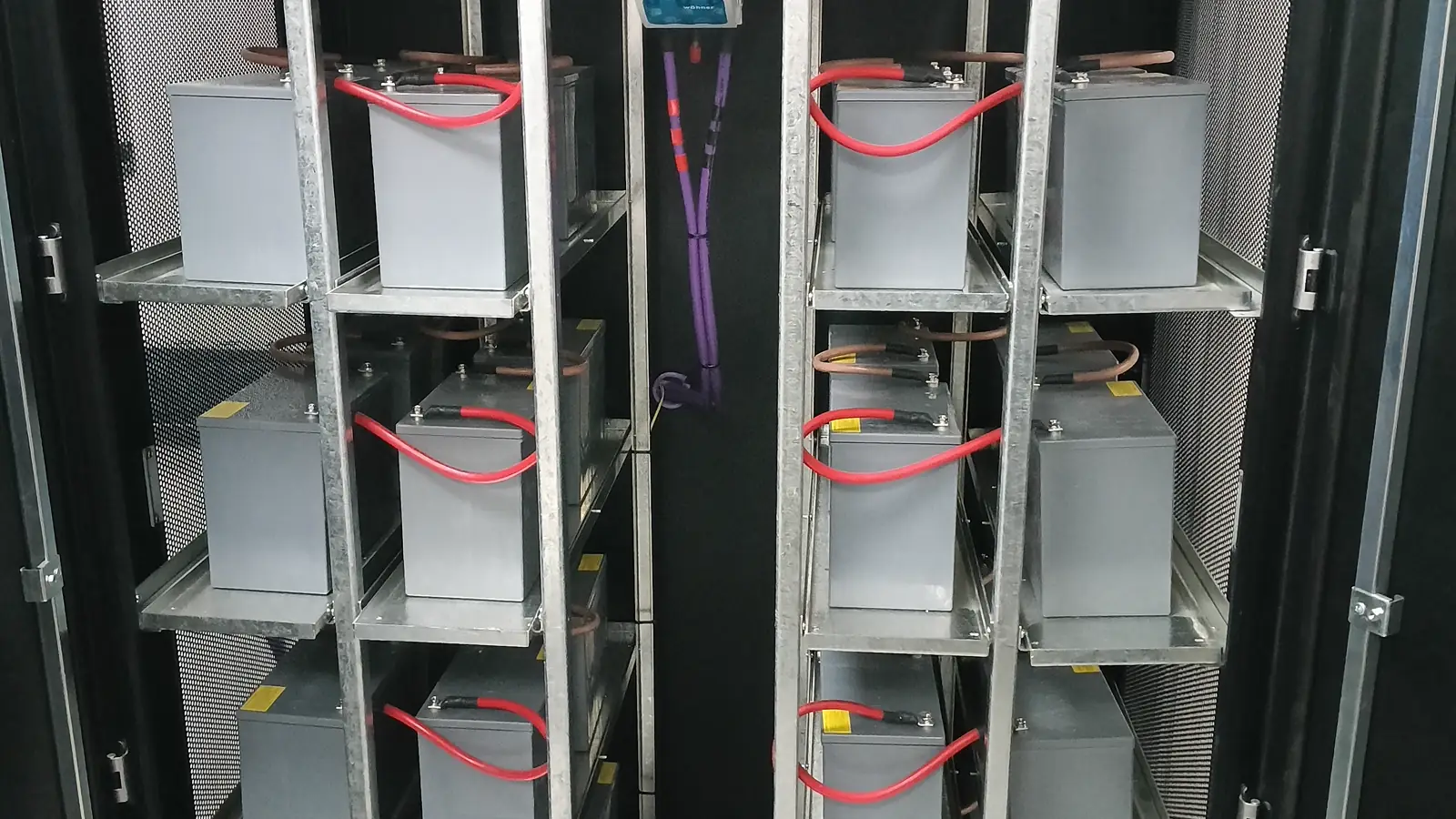 Banco de baterías de UPS montado en rack, con los puentes de conexión a la vista