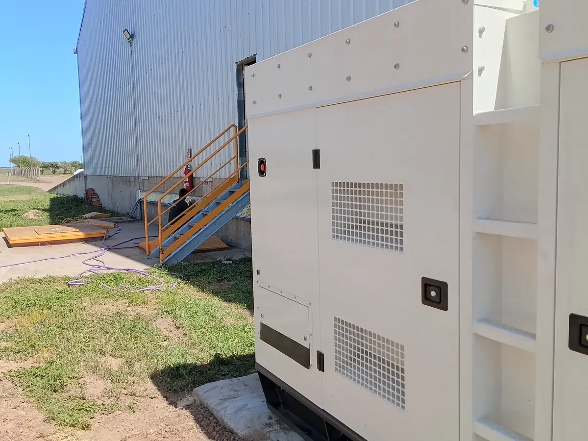 Grupo electrógeno instalado sobre su base junto a una nave industrial