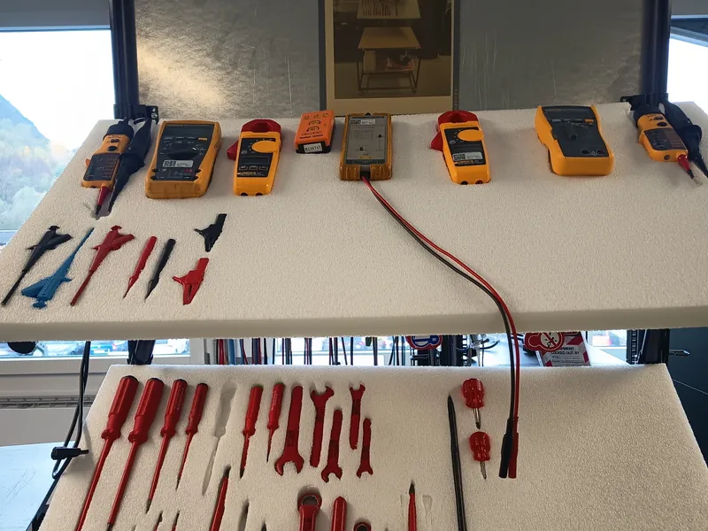 Instrumental de medición eléctrica y herramienta aislada ordenados sobre una mesa de trabajo