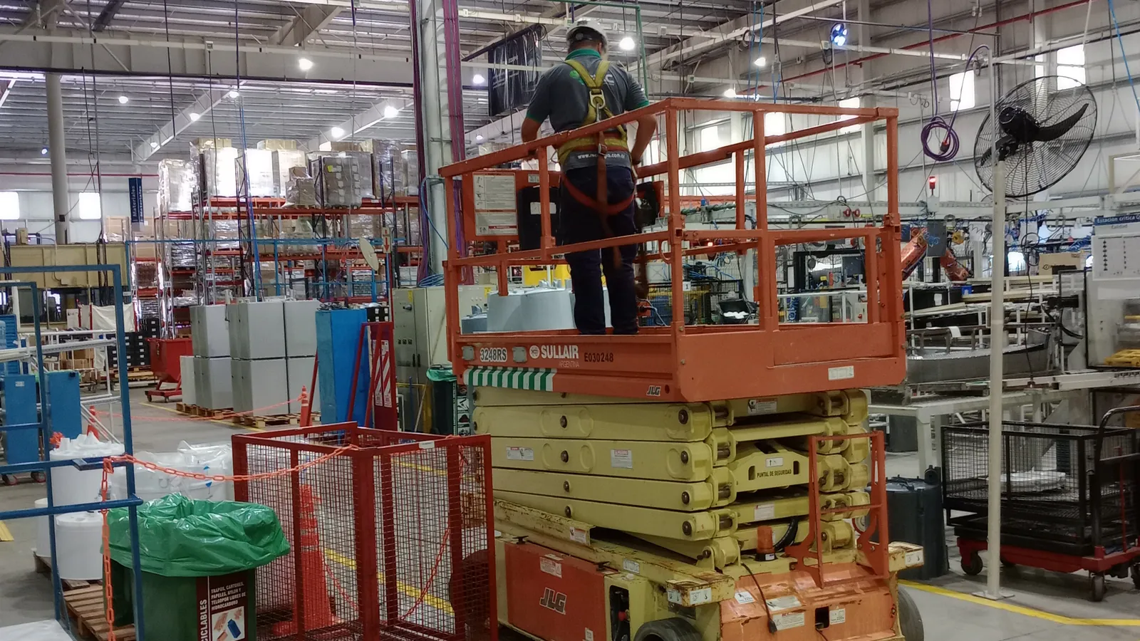 Técnico de REC ENERGÍA trabajando desde una plataforma elevadora dentro de una planta industrial