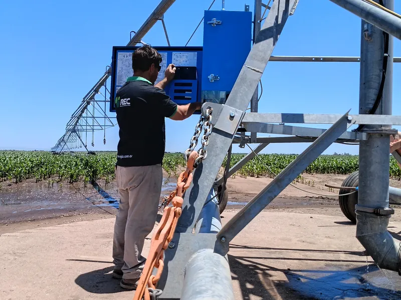 Técnico de REC ENERGÍA trabajando sobre el tablero de un equipo de riego por pivot en el campo