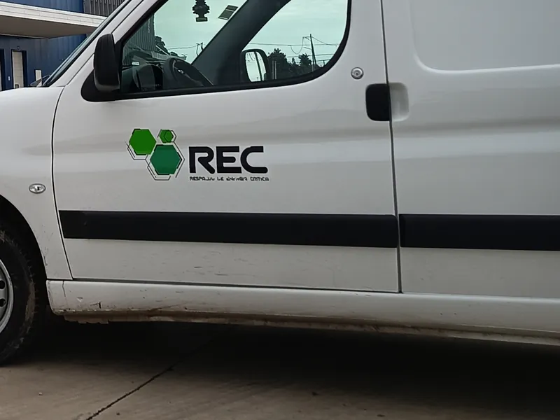 Utilitario de REC ENERGÍA con su logotipo, estacionado en la playa de una planta durante un servicio